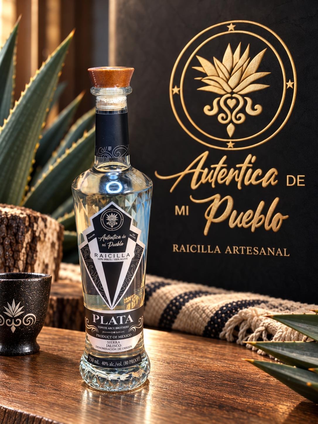 Bottle of Auténtica de Mi Pueblo Plata raicilla on a wooden surface with an agave plant and black branded signage